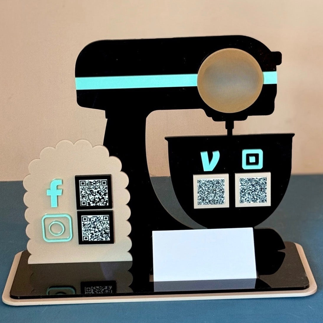 A business sign that is shaped like a mixer with qr codes to scan to pay or to search social media. Sign is custom made by Melissa Rae and Company. Made with Cast Acrylic. 